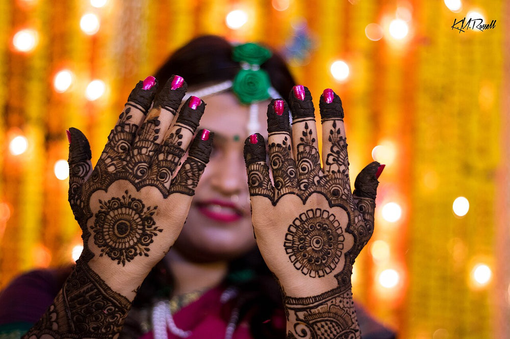 Henna-decorated hands at a gaye holud and mehndi, South Asian wedding