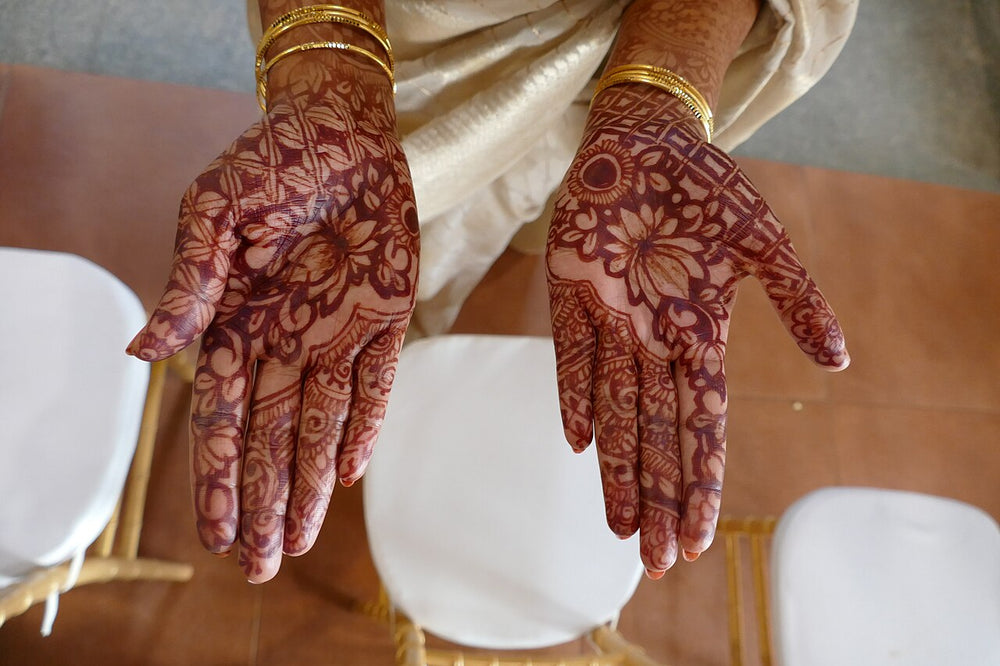 Henna-decorated hands held palms up at a mehndi, South Asian wedding