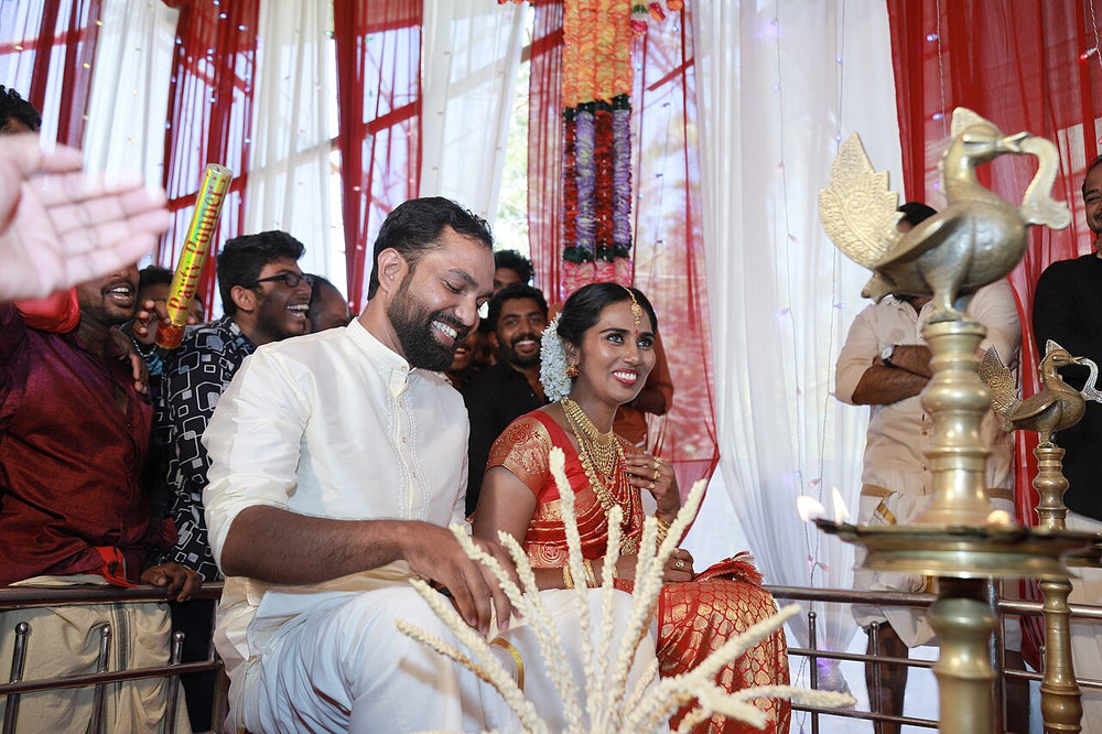 Couple in white mundu and red-and-gold silk at a Kerala wedding, South Asian wedding