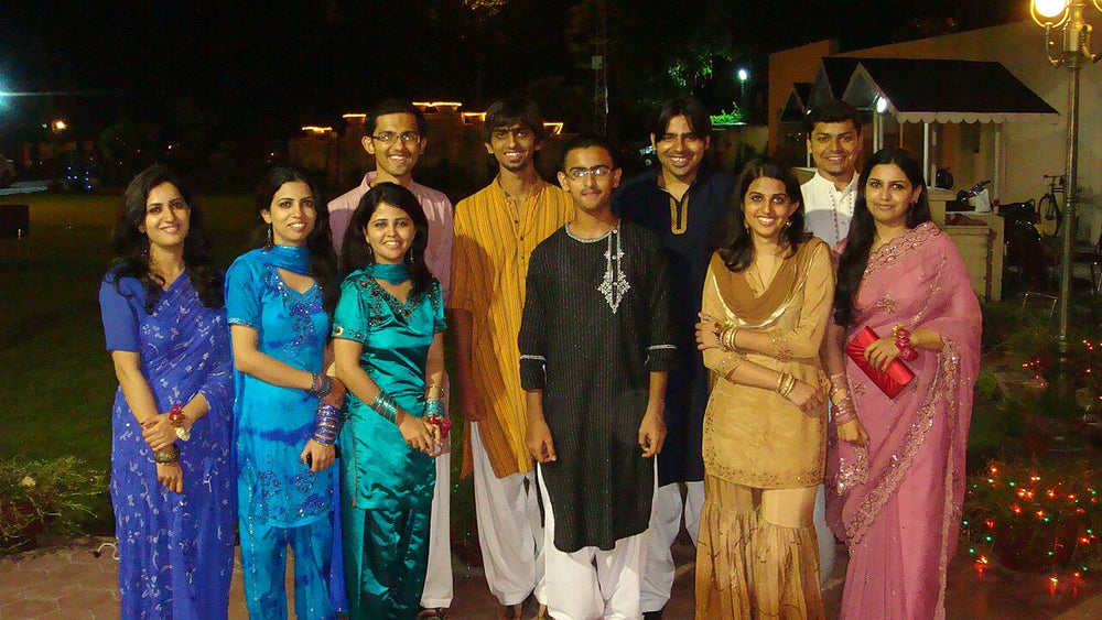 Guests in formal shalwar kameez, kurtas, saris and dresses posing together at an evening wedding in Lahore